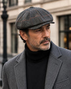 Boina newsboy gris de ocho paneles combinada con abrigo oscuro y sweater negro.