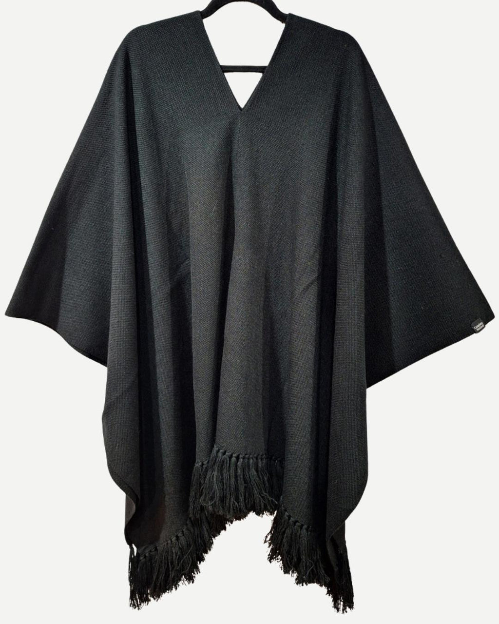 Manta Suspiro negra de alpaca y algodón en vista frontal, con diseño cerrado y flecos.