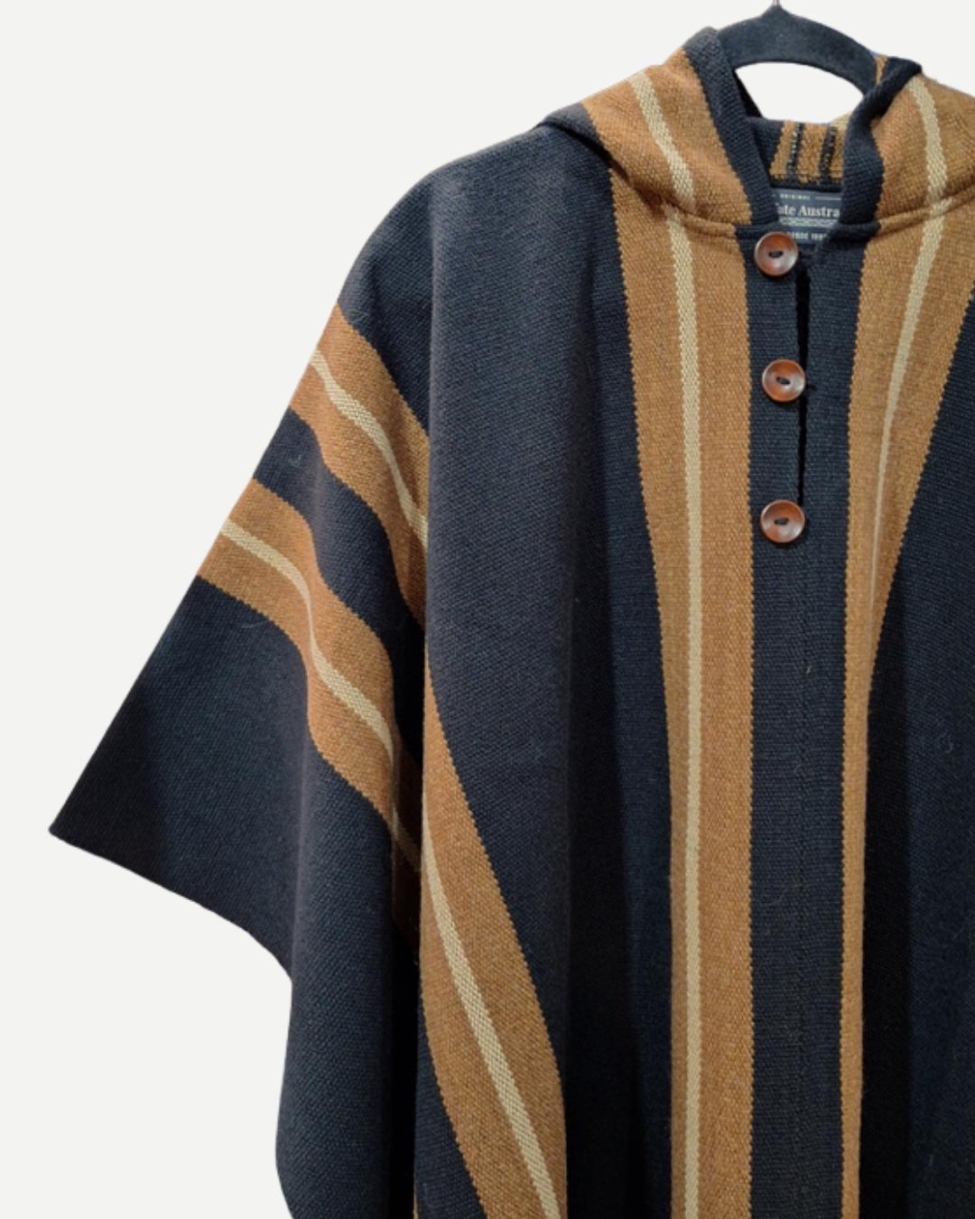 Detalle del Poncho Alerce Negro con botones frontales, capucha y tejido en franjas camel.