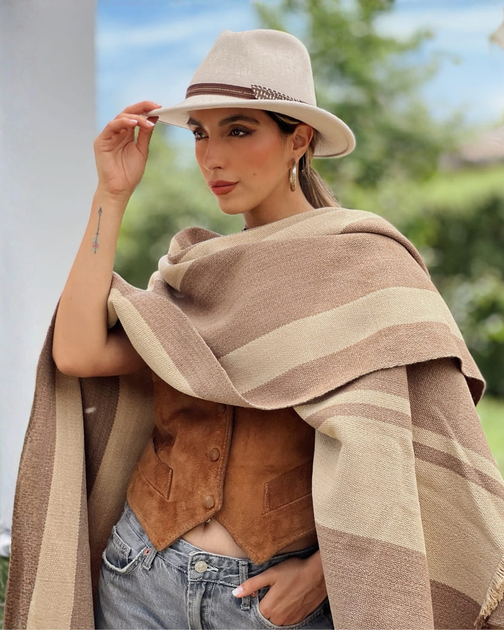 Look femenino con Poncho Ciprés té con leche y beige, prenda unisex de estilo sureño.