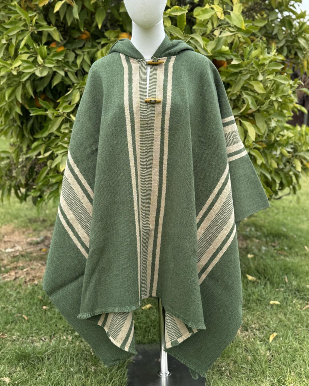 Poncho Coihue verde con franjas beige, capucha y botones frontales.