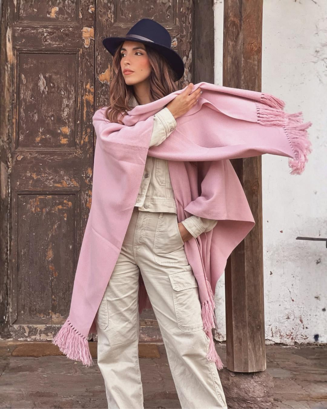 Mujer acomodando la Ruana Suspiro rosada de diseño abierto y caída amplia.