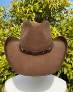 Sombrero Rustler de lana café con ala amplia, copa estructurada y detalles metálicos.